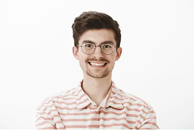 A heashot photo of our bespectacled team member Andrew Williams, smiling in a white and pink polo shirt.
